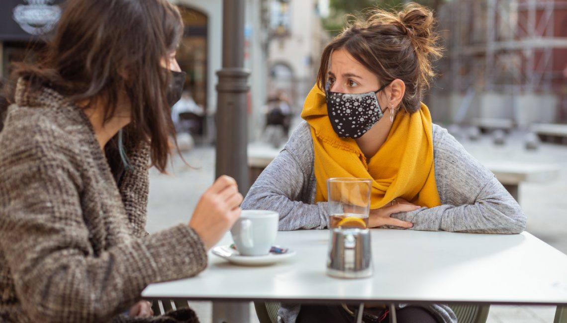 closeup-of-two-women-wearing-facemasks-during-the-covid-19-pandemic-sitting-at-cafe